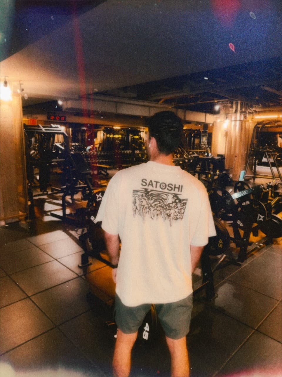 A light-colored Currency Collapse tee worn in a gym